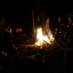 Gruppe sitzt bei Nacht rund ums Lagerfeuer und singt.