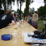 Menschen im Sommerlager sitzen an einer mit Wassergläsern bedeckten Bierbank