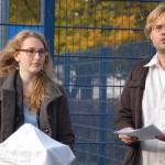 Nahaufnahme Mitarbeitende des Asa-FF vor sächsischem Verfassungsschutzgebäude während Rede vor Presse.