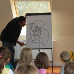 Mehrdad Zaeri zeichnet ein Bild mit Edding vor den Kindern im Kindergarten