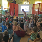 Kinder sitzen auf dem Boden vor der provisorischen Leinwand beim Vortrag: Intelligenz und Kultur bei Delfinen und Walen (Diplom-Biologe Fabian Ritter)