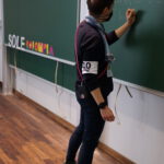 Eine Person mit einer Armbinde schreibt etwas an eine Tafel. Auf der Tafel ist SOLE COLOMBIA zu lesen.