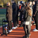 Eine Gruppe Personen am Spielfeldrand eines Fußballfelds