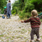 Kleinkind von hinten schaut in Richtung der Mutter im Sommerlager