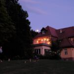 Teilnehmende beim Spielen auf dem Rasen vor der Unterkunft während der Abenddämmerung