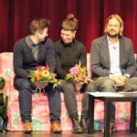 Preisträgerinnen und Preisträger mit Blumenstrauß auf einem Sofa auf der Bühne