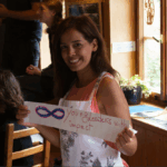 Lächelnde Teilnehmerin hält Papier in der Hand worauf steht: "8 young Leaders with impact"