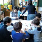 Schülerinnen und Schüler beim Gruppenbasteln an runden Tischen