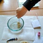 Ein Stück Stoff wird mit einer Zange in eine Schüssel mit Wasser getunkt