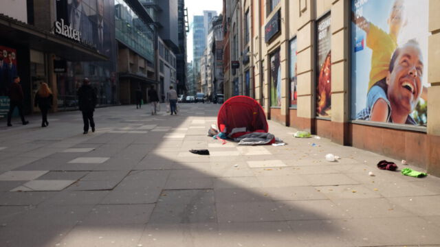 auf den Straßen von Manchester (c)Frauke Frech Einkaufsstraße in Manchester, ein Schlafsack der nach der Nacht zurückgelassen wurde liegt neben einem Geschäft. Passantinnen und Passanten gehen daran vorbei.
