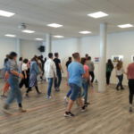 Teilnehmende beim Szenischen Spiel in einem leeren Raum. Sie gehen synchron in eine Richtung.