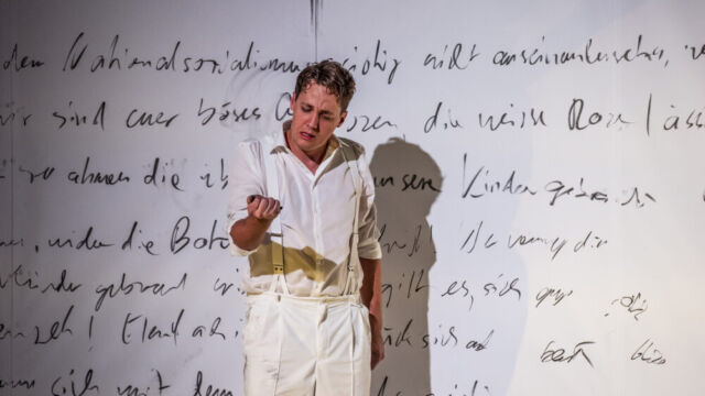 Foto: Nasser Hashemi Erschrockener trauriger Schauspieler vor einer mit Text bekritzelten Wand