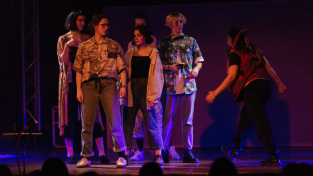 Eine Schauspielerin läuft bestimmt auf eine Gruppe von Schauspielenden zu